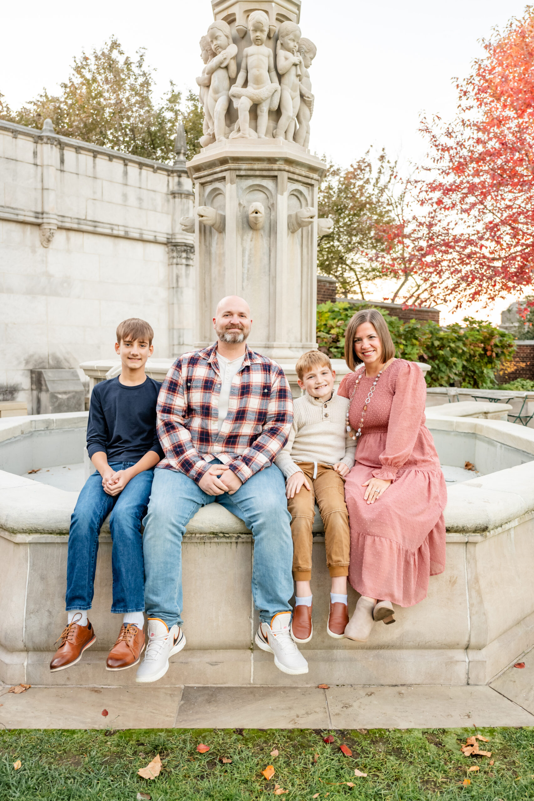 Family posing in front of colorful fall foliage at Hartwood Acres Mansion in Pittsburgh during a fall mini session, taken by Carly Ferraco Photography.