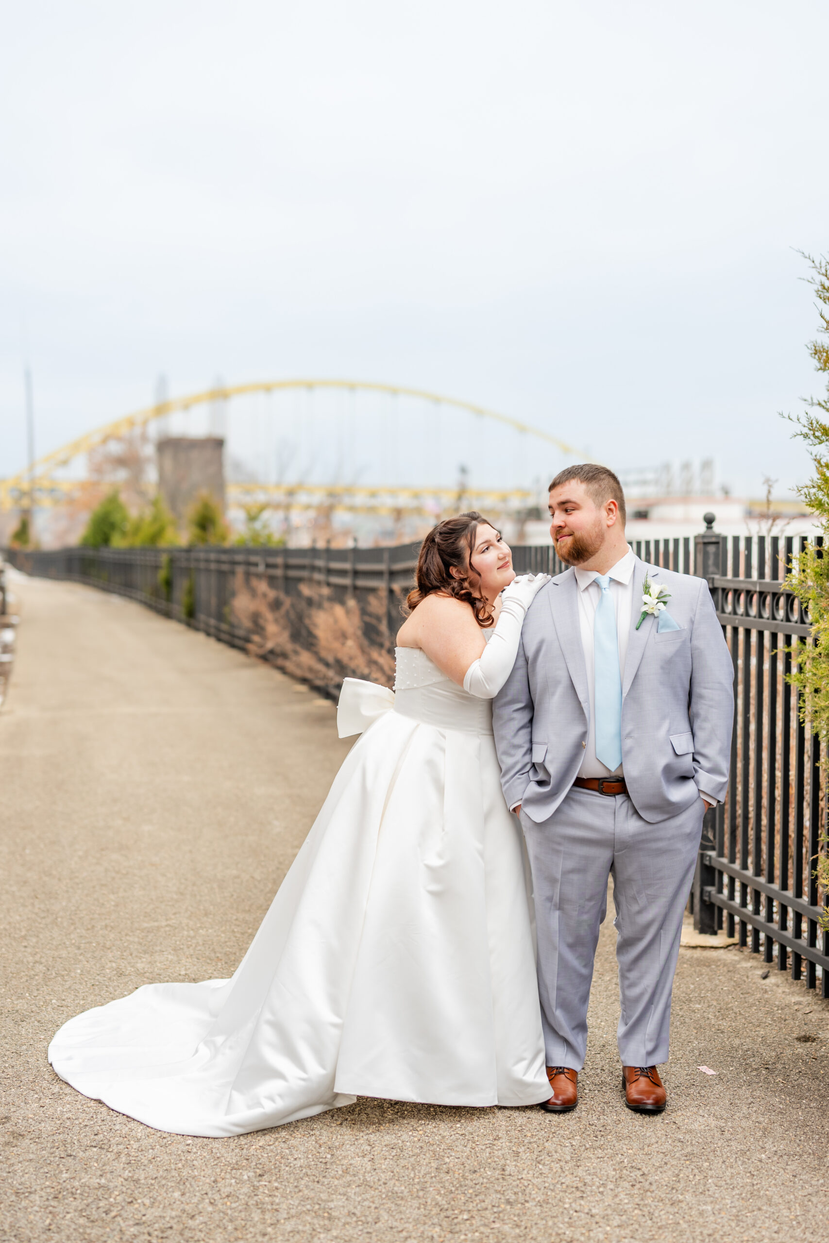 Winter Wedding in Pittsburgh. Bride and groom posing outside THe Sheraton Station Square with yellow bridge behind them.
